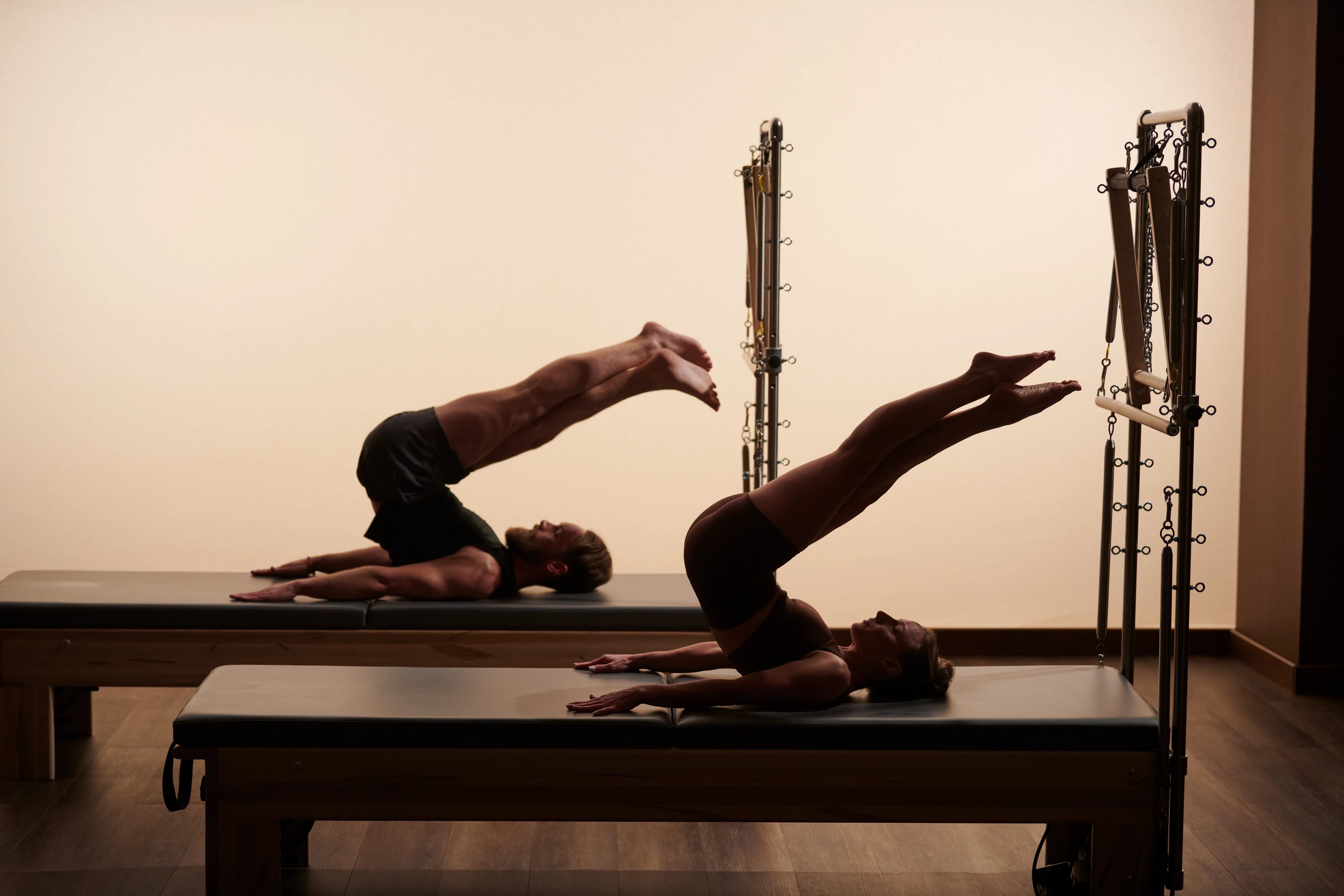 Two clients performing refined, symmetric Pilates technique